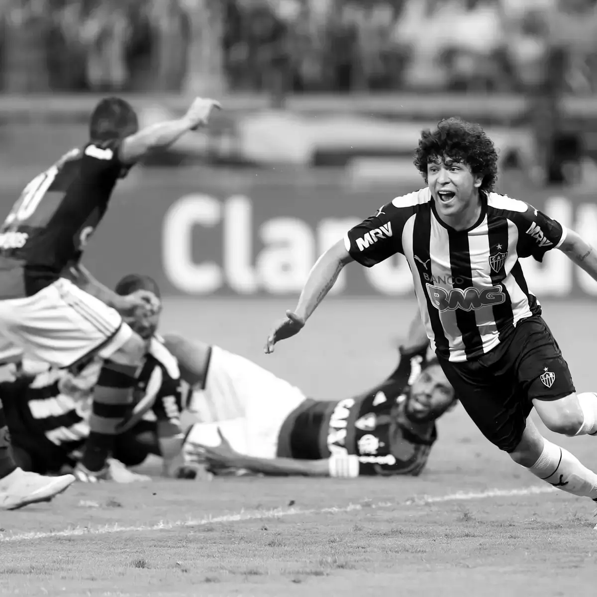 Jogador do Atlético corre para comemorar um gol, com jogadores do Flamengo caídos no gramado